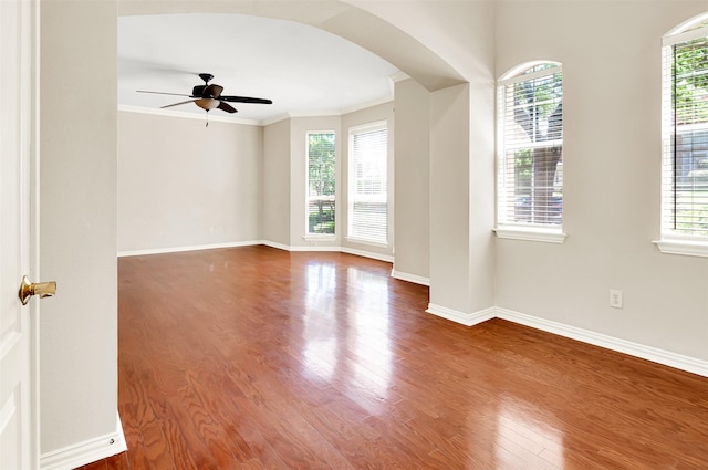 spare room with arched walkways, plenty of natural light, ornamental molding, and ceiling fan