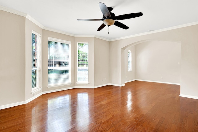 empty room with a healthy amount of sunlight, arched walkways, a ceiling fan, and wood finished floors