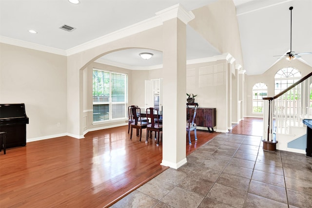 entrance foyer with plenty of natural light, arched walkways, ceiling fan, and stairway