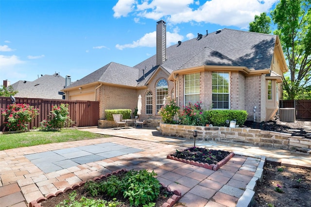 back of house featuring brick siding, a chimney, a patio, and a fenced backyard