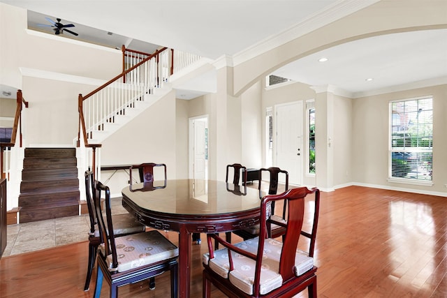 dining area featuring visible vents, ornamental molding, wood finished floors, baseboards, and arched walkways