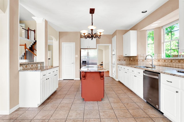 kitchen with light stone countertops, a center island, a sink, appliances with stainless steel finishes, and backsplash