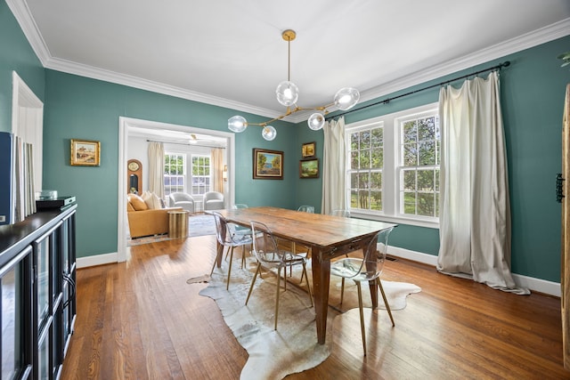 dining room featuring crown molding, baseboards, and wood finished floors
