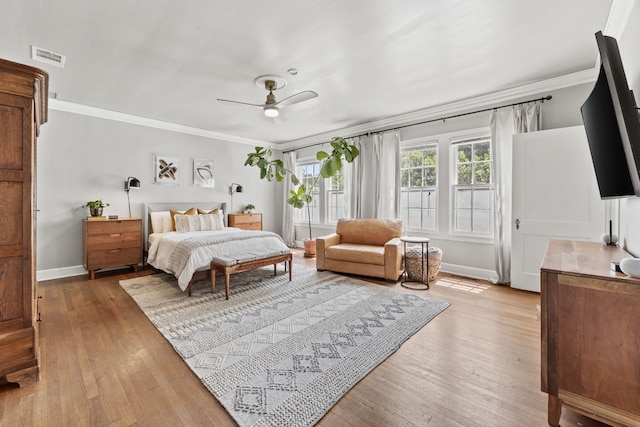 bedroom featuring crown molding, visible vents, baseboards, hardwood / wood-style flooring, and a ceiling fan