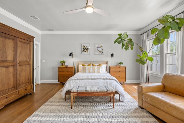 bedroom with baseboards, ornamental molding, wood finished floors, and visible vents