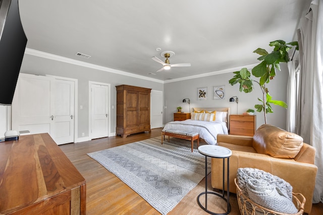 bedroom featuring ceiling fan, visible vents, crown molding, wood finished floors, and baseboards