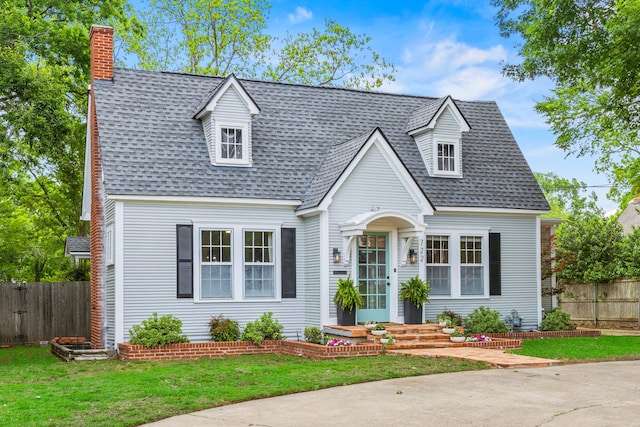 cape cod house with a shingled roof, a front lawn, fence, and a chimney