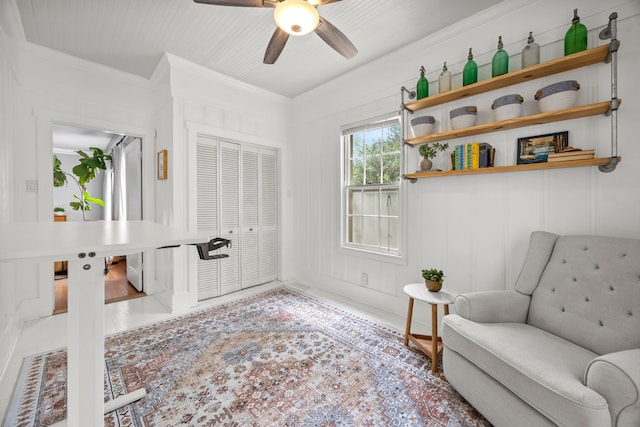 living area featuring crown molding and a ceiling fan