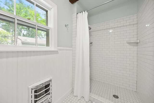 full bathroom with tile patterned floors, heating unit, a stall shower, and wainscoting