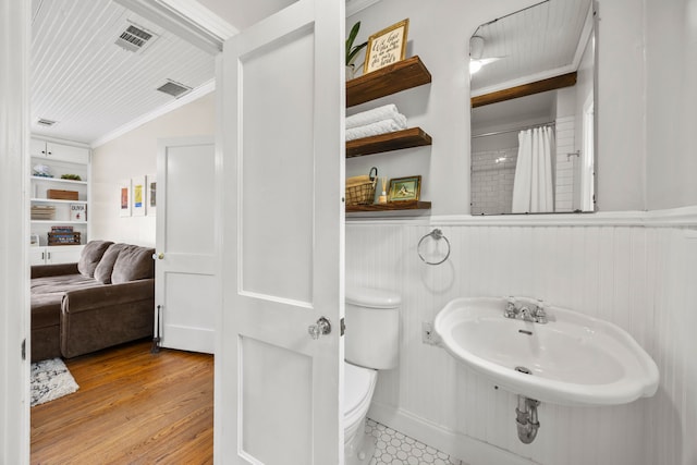 bathroom featuring visible vents, vaulted ceiling, a sink, toilet, and ornamental molding