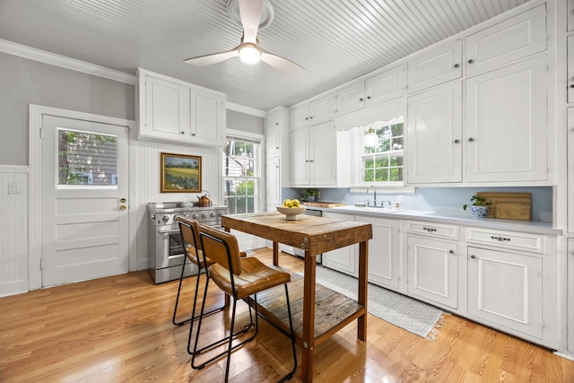 kitchen with a sink, light countertops, white cabinetry, and stainless steel stove