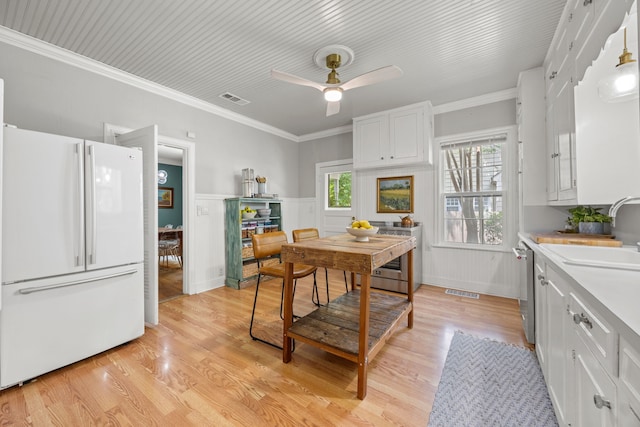 kitchen featuring a sink, light countertops, light wood-style flooring, freestanding refrigerator, and white cabinetry