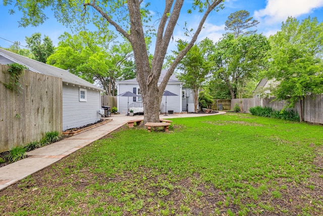 view of yard with a fenced backyard, a patio, an outbuilding, and a shed