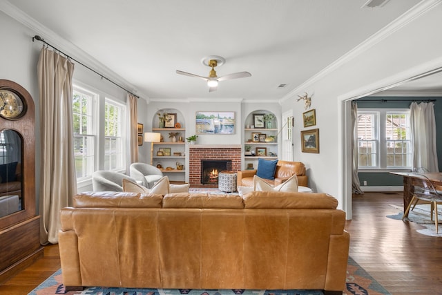 living area with a brick fireplace, a ceiling fan, ornamental molding, and dark wood-style flooring