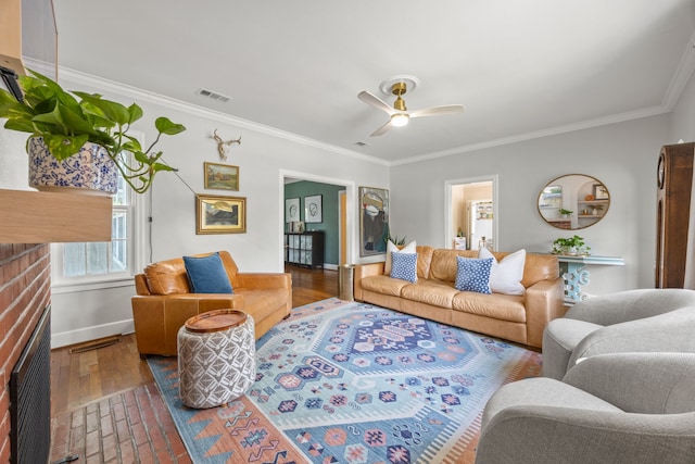 living room with crown molding, ceiling fan, baseboards, wood finished floors, and visible vents