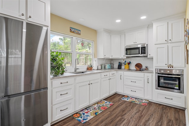 kitchen featuring decorative backsplash, dark wood-style flooring, a sink, stainless steel appliances, and white cabinetry