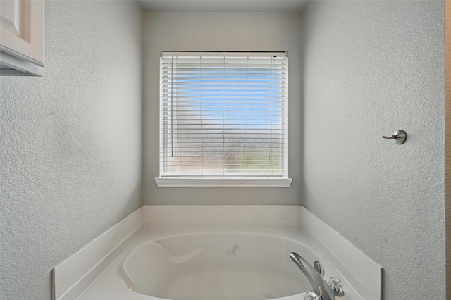 bathroom with a textured wall and a bath