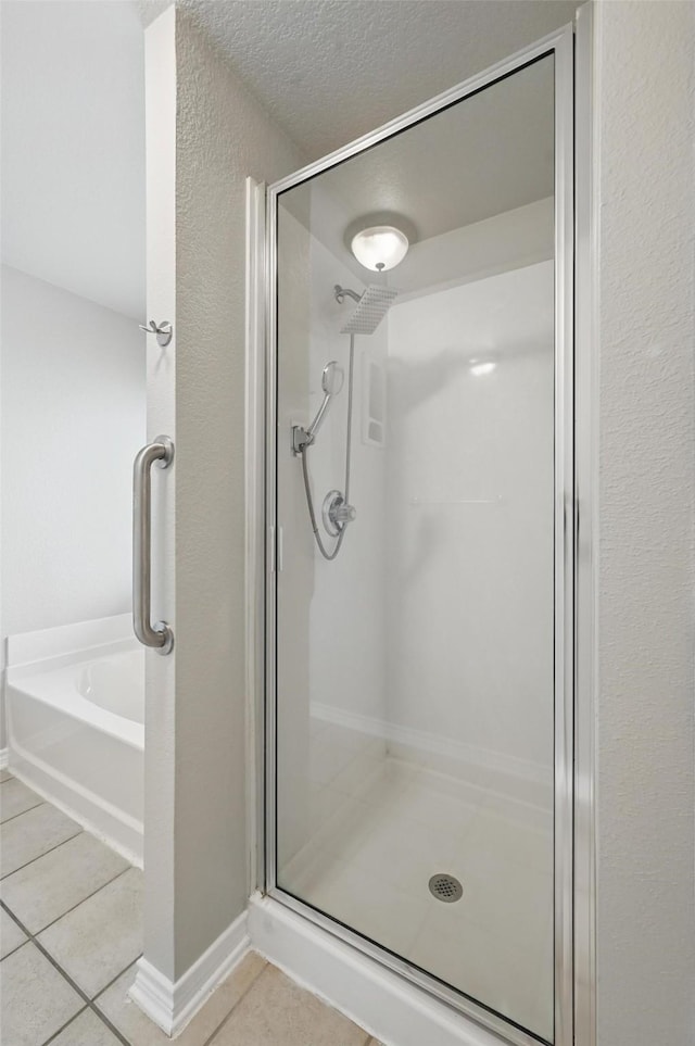 bathroom featuring a textured ceiling, tile patterned floors, a shower stall, and a garden tub