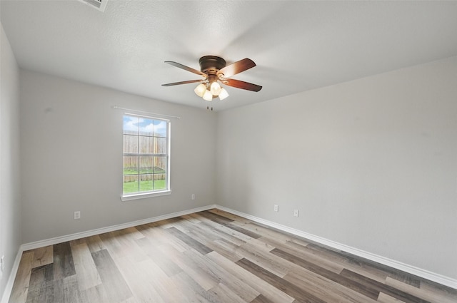 unfurnished room with light wood-type flooring, a ceiling fan, and baseboards