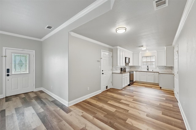 kitchen with visible vents, electric range oven, light wood finished floors, and backsplash