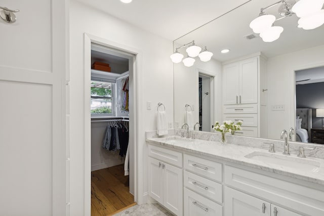 ensuite bathroom with visible vents, a sink, connected bathroom, and double vanity