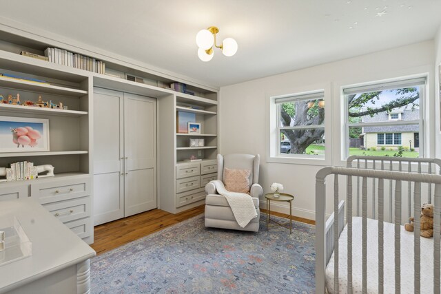 bedroom with a crib, baseboards, and wood finished floors