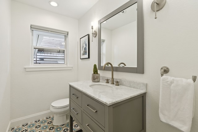 bathroom featuring toilet, baseboards, and vanity