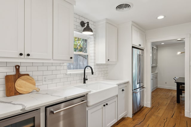 kitchen with visible vents, a sink, white cabinets, wine cooler, and stainless steel appliances