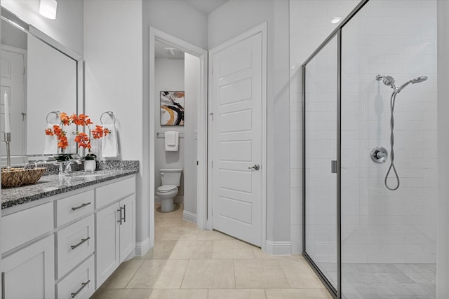 full bathroom featuring a shower stall, vanity, toilet, tile patterned floors, and baseboards