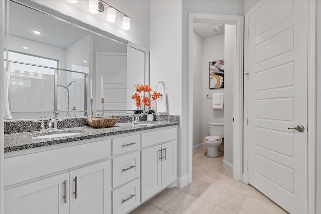 bathroom with a stall shower, toilet, double vanity, baseboards, and tile patterned floors