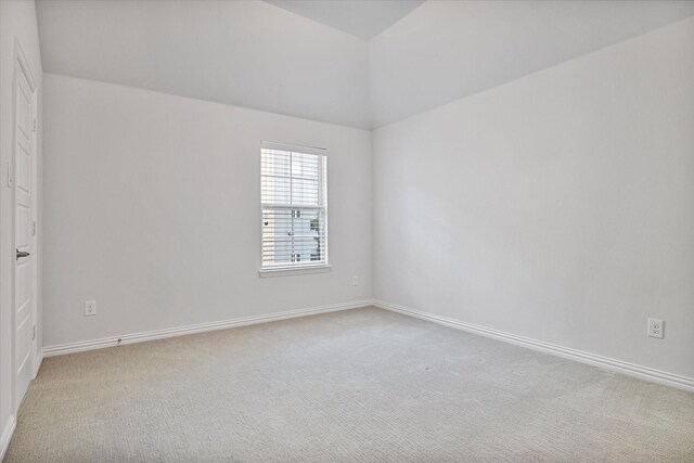 unfurnished room featuring carpet, baseboards, and lofted ceiling