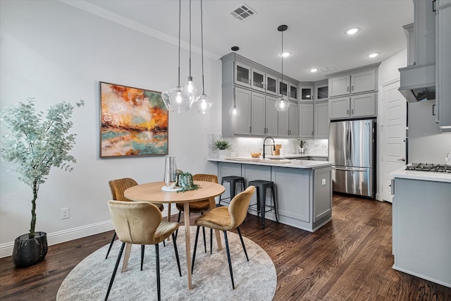 kitchen with gray cabinetry, freestanding refrigerator, a peninsula, glass insert cabinets, and recessed lighting