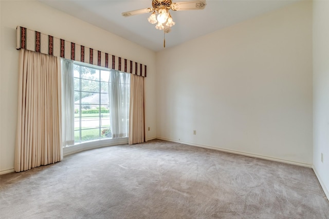 carpeted empty room with baseboards and a ceiling fan