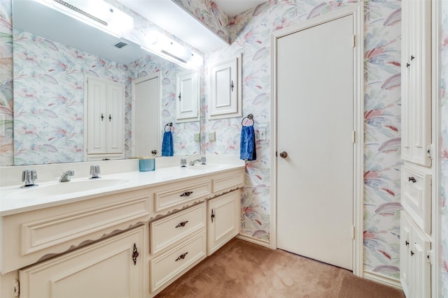 bathroom featuring visible vents, a sink, double vanity, and wallpapered walls