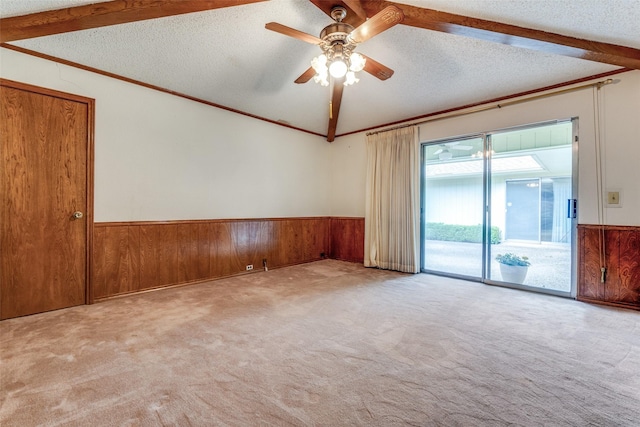 spare room featuring wooden walls, ceiling fan, vaulted ceiling, and wainscoting
