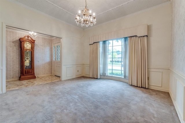 carpeted empty room featuring ornamental molding, wainscoting, a decorative wall, and a notable chandelier