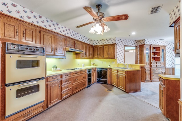 kitchen with visible vents, white appliances, wallpapered walls, brown cabinets, and a sink