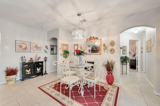 tiled dining room featuring arched walkways, baseboards, visible vents, and an inviting chandelier