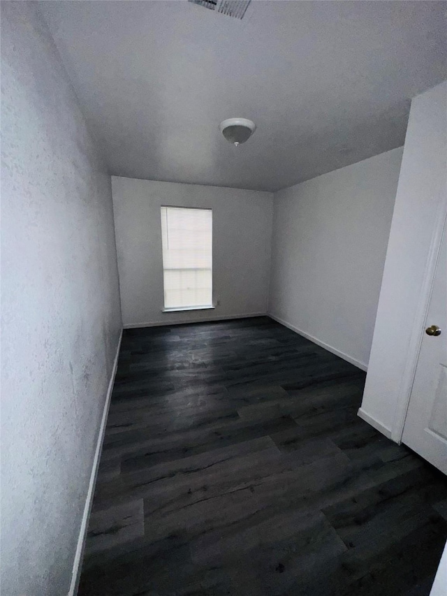 7539 Red Bud Dr, Dallas, TX 75227 - spare room featuring a textured wall, baseboards, visible vents, and dark wood-style floors
