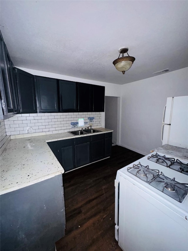 7539 Red Bud Dr, Dallas, TX 75227 - kitchen featuring dark cabinetry, a sink, backsplash, and white appliances