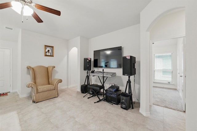 living area featuring arched walkways, a ceiling fan, visible vents, and baseboards