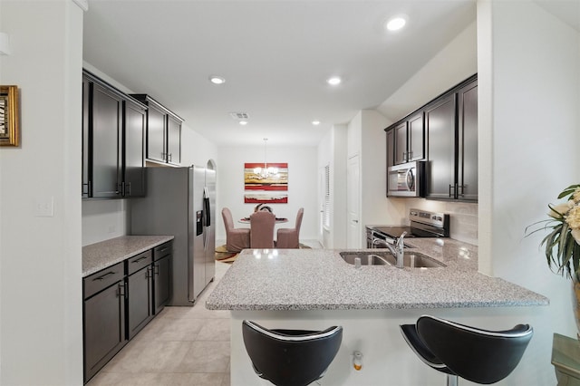kitchen with light stone counters, stainless steel appliances, recessed lighting, a peninsula, and visible vents