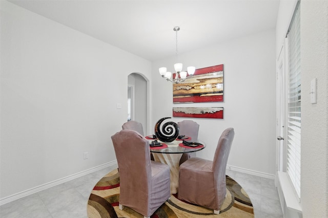 dining room with an inviting chandelier, arched walkways, and baseboards