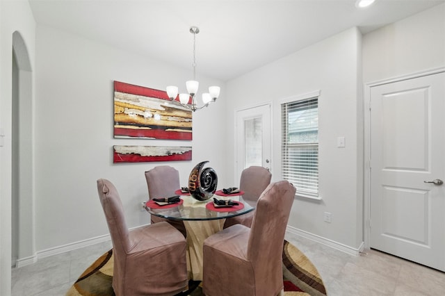dining area with arched walkways, baseboards, an inviting chandelier, and light tile patterned floors
