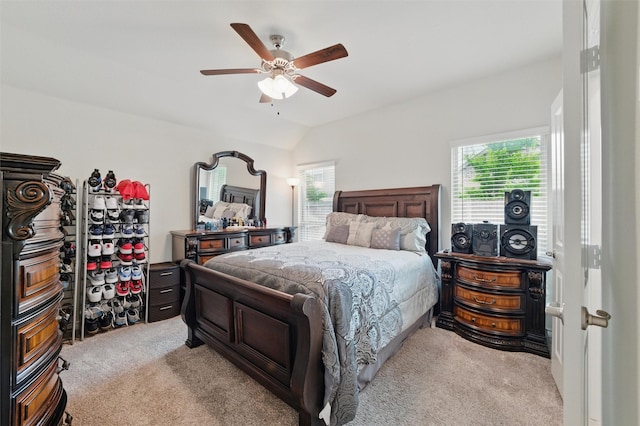bedroom with a ceiling fan, vaulted ceiling, and light carpet