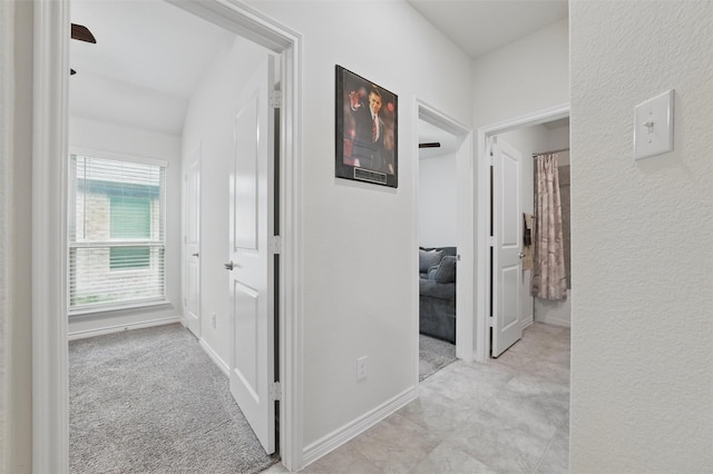 hall with baseboards and light colored carpet