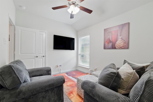living area featuring baseboards, ceiling fan, and lofted ceiling