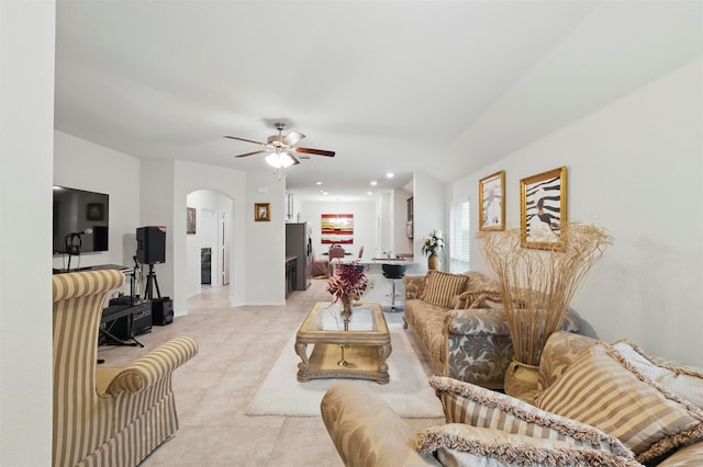 living area featuring arched walkways, a ceiling fan, recessed lighting, and light tile patterned floors