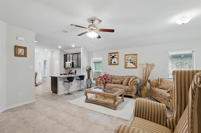 living area with light tile patterned floors, baseboards, plenty of natural light, and a ceiling fan