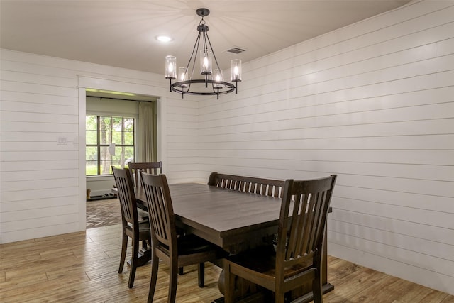 dining room featuring a chandelier, wood walls, visible vents, and light wood-style flooring